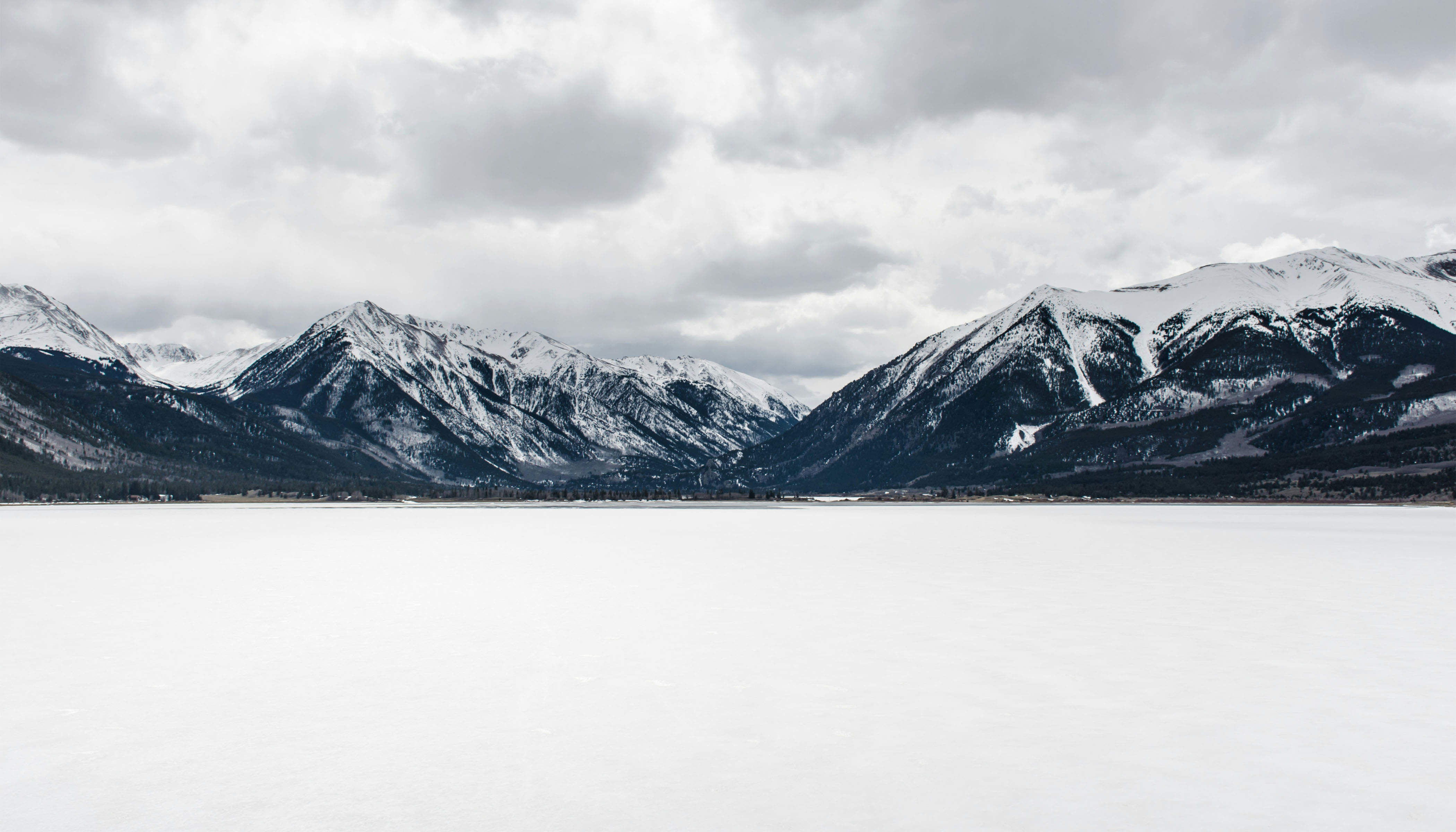 An Frozen Snow-Covered Body of Water Near Mountain Peak During Daytime