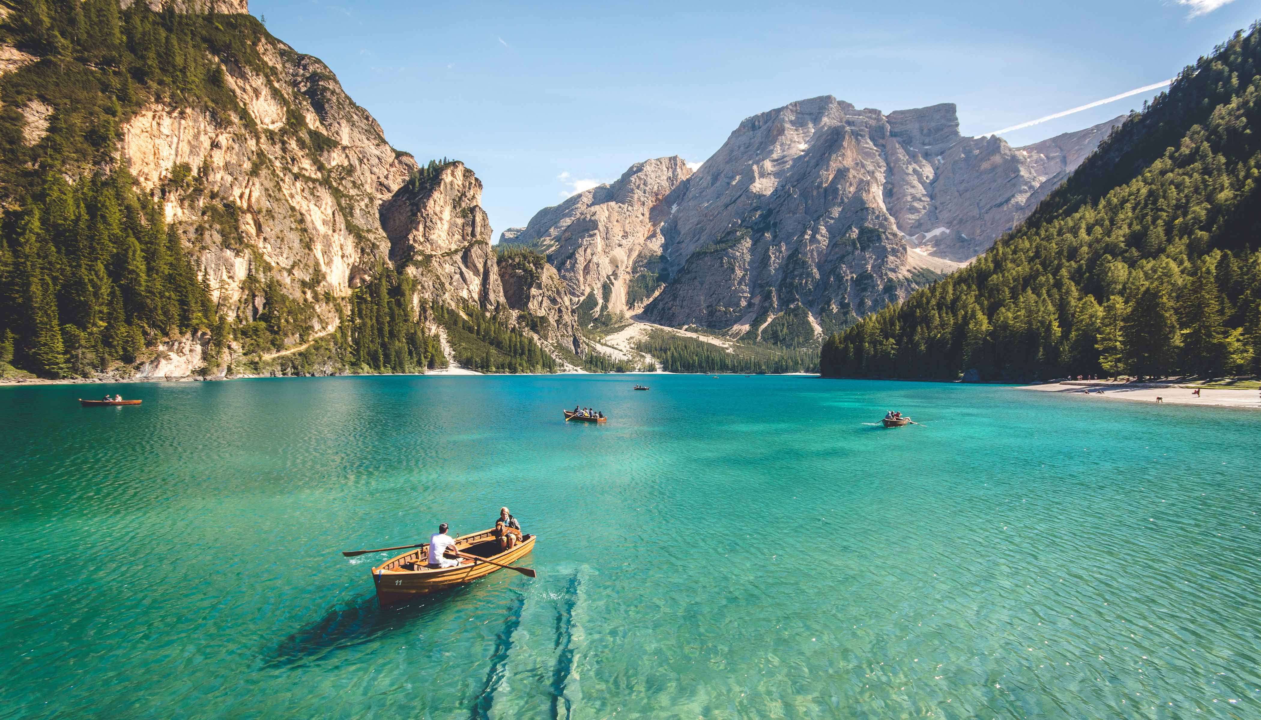 Three Rowboats on the Water With Cliffs Behind